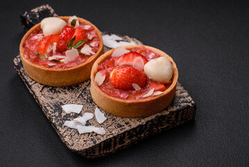 Delicious fresh sweet tartlets with strawberries and coconut flakes