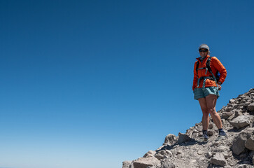 Female Hiker On Narrow Rocky Trail Against Blue Sky