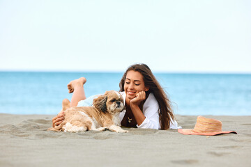 Young woman and her dog enjoy in day on sandy beach during summer.
