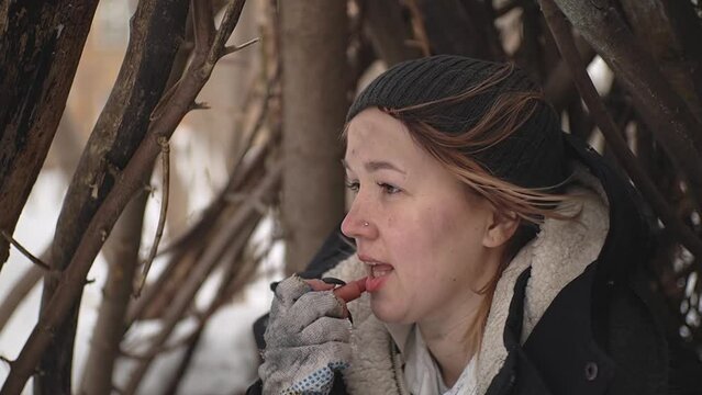 homeless woman paints her lips with red lipstick. homeless woman in the forest. slow motion video. High-quality shooting in Full HD