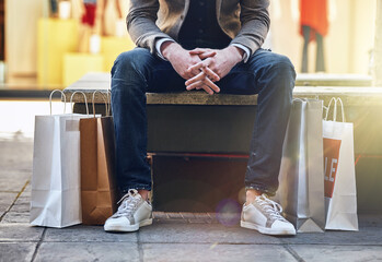 City, man sitting and sale with shopping bags on floor, sidewalk or street with sneakers, relax or...