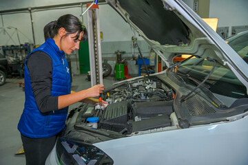 Fototapeta na wymiar Young female mechanic, checking the air filter, of a car engine.