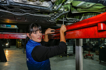 Young female mechanic, working on the repair of a car engine.