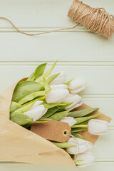 Bouquet of white tulips on a green wooden background, copy space. Easter. Top view