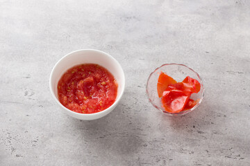 Fresh tomato puree and tomato peel after grinding on a gray textured background. Stage of cooking homemade food