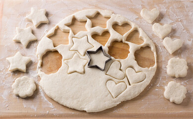 The process of cutting cottage cheese cookies with molds from soft dough rolled out on a board. Cooking delicious homemade cakes.