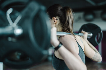Young woman working out with a barbell at the gym 

