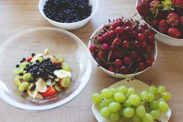Delicious and healthy breakfast with fruits and berries. Fruits and berries in plates on the kitchen table.