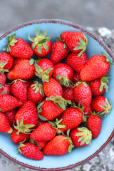 Turquoise bowl with fresh strawberries, served in a garden. Top view.