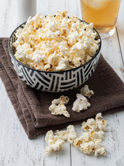 Popcorns on a bowl with salt over and soda wooden table