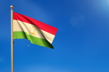 Tajikistan. Flag blown by the wind with blue sky in the background.
