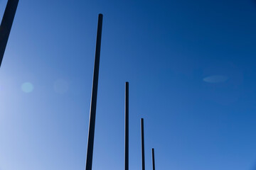 a group of empty metal flagpoles against a blue sky background