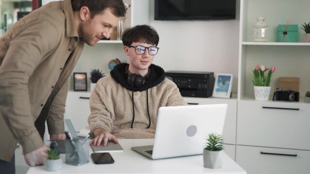 The supervisor approaches the employee in the office.The supervisor praises the employee for their good work.they give each other a high-five and the supervisor taps the employee on the shoulder.