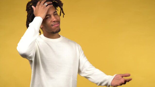 Young black male showing a facepalm expression on yellow background