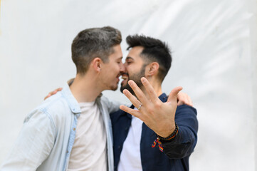Happy young ethnic gay couple kissing after proposal