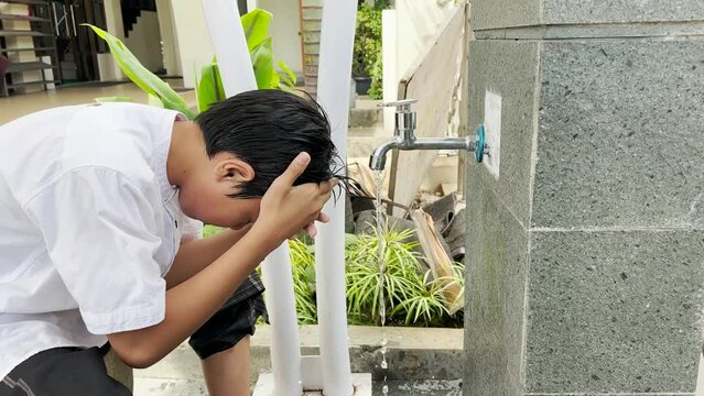 Muslim kid wiping the head  and cleanse ear when take ablution or wudu before praying salah
