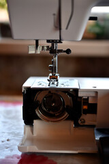 A white sewing machine in the room. Processing of clothes with a sewing machine.