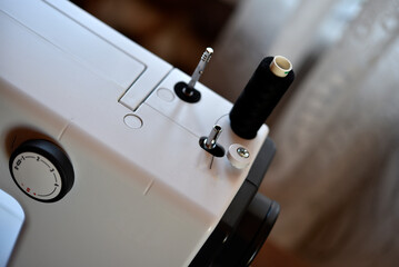 A white sewing machine in the room. Processing of clothes with a sewing machine.