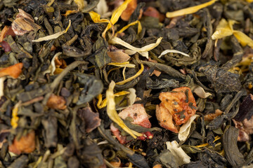 A large amount of dry green tea with pieces of fruit