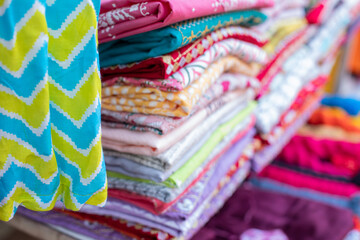 Fabric store, large selection. Bright fabrics with various patterns hang and lie in large piles on eastern market.