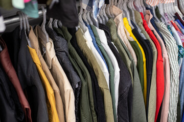 Clothing discounter. Men's monochrome long sleeve shirts of different sizes hang on hangers in clothing store. Outlet.