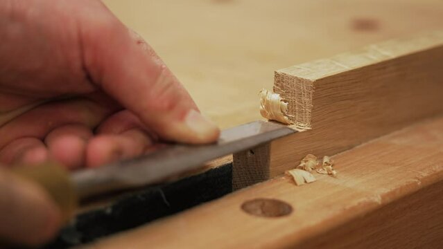 Hands of a carpenter carving wood with a chisel to smooth out wooden plank closeup. High quality 4k footage