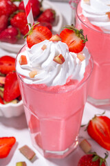 Rhubarb and strawberry milkshake or smoothie, refreshing summer drink, Healthy dieting and antioxidant summer beverage with whipped cream, fresh rhubarb, strawberry slices, on white kitchen table