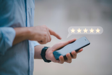 Customer service experience and business satisfaction survey.close up Man hand using smartphone with popup five star icon for feedback review satisfaction service.