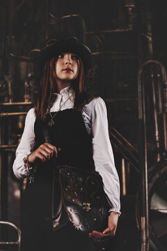 Portrait of gorgeous teen girl wear steampunk image with leather bag posing at industrial room. Toned image of pensive stylish steampunk girl model actress. Fashionable concept. Copy ad text space