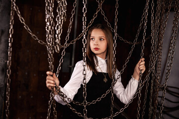 Portrait of lovely stylish teen girl wear retro style image posing in dark industry room with chains, looking away. Pensive lovely girl model actress. Fashionable style concept. Copy ad text space