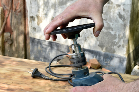 The man's hand is inserted into the drill chuck circle for grinding.