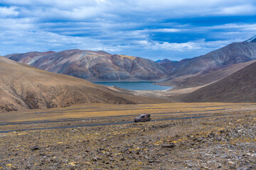car driving through the desert. Landscape of Desert mountains against clouds sky at Ladakh, India