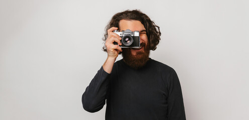 Fototapeta na wymiar Banner size shot of a long hair bearded man looking through a photo camera.