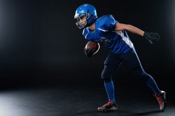 Full length portrait of a man in a blue american football uniform against a black background....