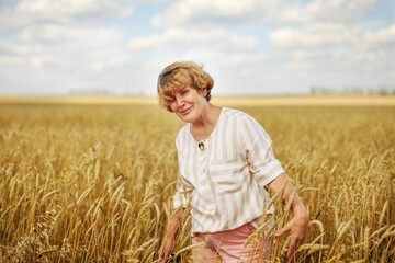 Naklejka na ściany i meble Portrait of a happy smiling senior woman in wheat field