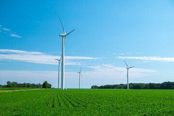 Close view of onshore horizontal axis wind turbine (windmill) in green field, deep blue sky, sunny...