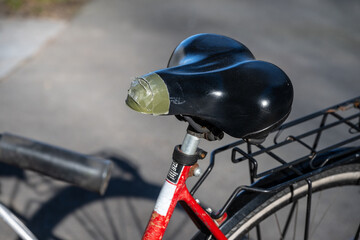 Tape mended bicycle seat on a red bike. - obrazy, fototapety, plakaty