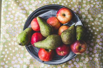 Red apples and green pears on a plate.
