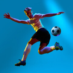 Fototapeta na wymiar One soccer football player jumping and kicking the ball in neon light. Goal in motion. Concept of success, leadership, competition