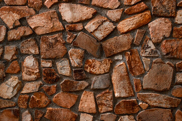 wall with a pattern of stones, of different shapes and sizes, with similar colors towards brown, which can serve as a decorative background.