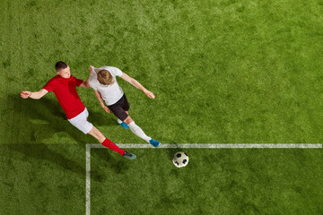 Fototapeta premium Two men, soccer players performing football play over professional stadium. All players wear unbranded clothes. Concept of professional sport