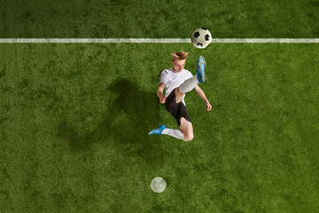 One soccer football player jumping and kicking the ball over field background. Jump ball hit. Concept of action, energy, sport, team game