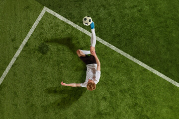 Professional football, soccer player in sportswear kicking the ball with leg from penalty area over field background. Aerial view. Concept of team game, sport