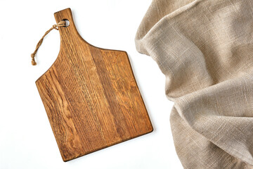 A beige wooden cutting board and a rough beige linen napkin on a