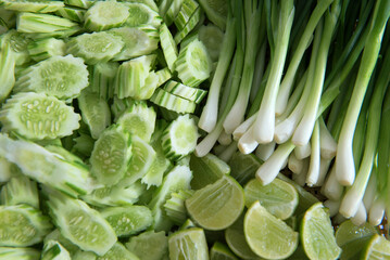 Closeup of freshly harvested vegetables (cucumber, lime, spring onion), top view