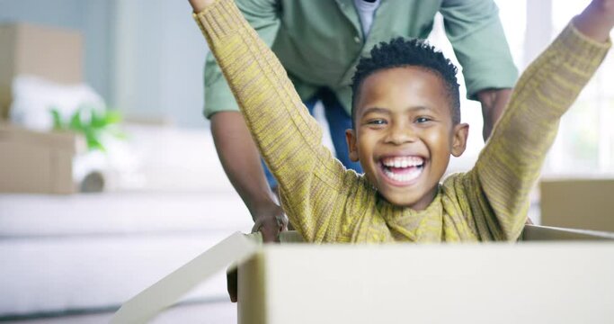 Happy, playful and child in a box with father pushing for play, moving and enjoyment in a new home. Smile, excited and portrait of an African boy kid pushed in boxes by dad for relocation in a house