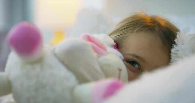 Child, bed and teddy bear in home bedroom while happy and excited for morning play, comfort or love. Girl kid with stuffed animal toy for development, hug and to feel safe on fluffy pillow in a house