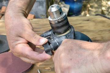 The man's hand fix the handle of the drill on the body of the tool.