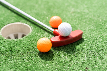 Close-up of miniature golf hole with bat and ball