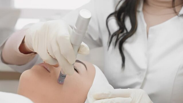 Professional fractional mesotherapy as an ideal way to improve the condition skin under guidance an experienced cosmetologist in beauty salon. A young woman rests and relaxes during the procedure
